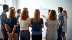 Personen stehen vor einem Flipchart